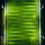 Aerial view of a floodlit soccer stadium and pitch at night