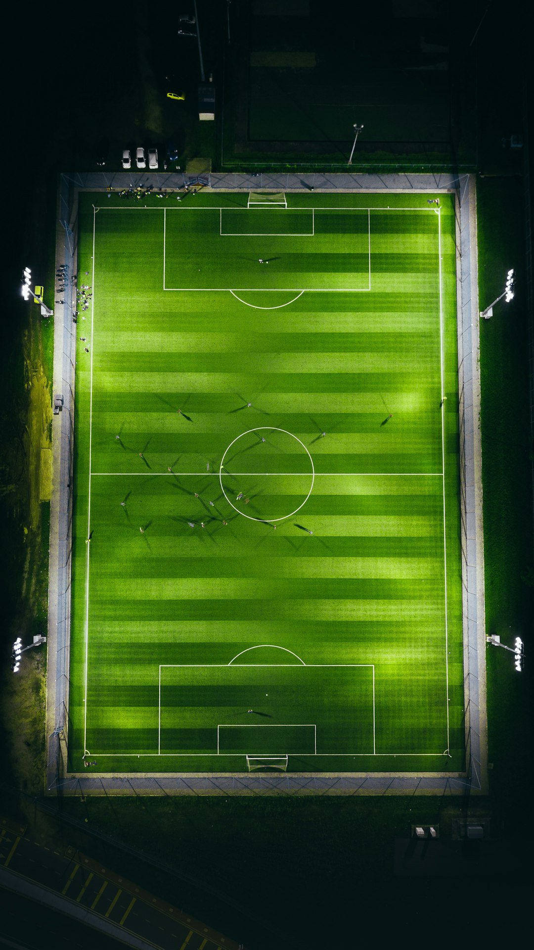 Aerial view of a floodlit soccer stadium and pitch at night